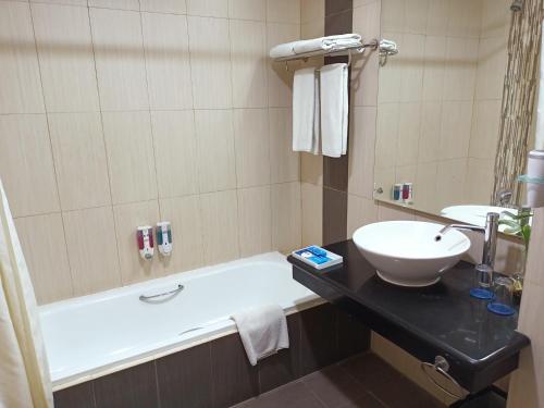 a bathroom with a sink and a bath tub at Days Hotel & Suites by Wyndham Jakarta Airport in Tangerang