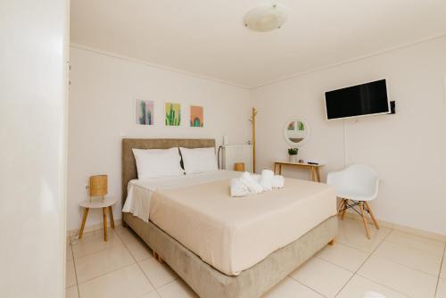 a white bedroom with a bed and a flat screen tv at CACTUS - Blooming Garden Apartments in Kalamata