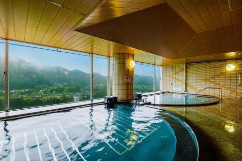 a large swimming pool in a building with a large window at KAMENOI HOTEL Nagatoro Yorii in Yorii
