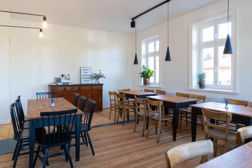 uma sala de jantar com mesas, cadeiras e janelas em Das Timmann em Stelle