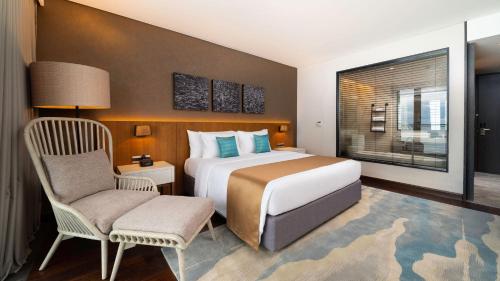 a bedroom with a bed and a chair and a window at The Reef Island Resort Mactan, Cebu in Mactan