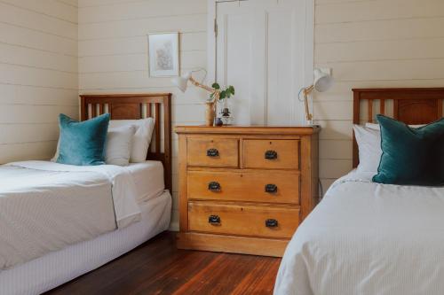 a bedroom with two beds and a wooden dresser at Naivasha Cottage in Deloraine