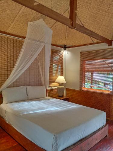 a bedroom with a bed with a mosquito net at Mookies Bungalows in Koh Mook