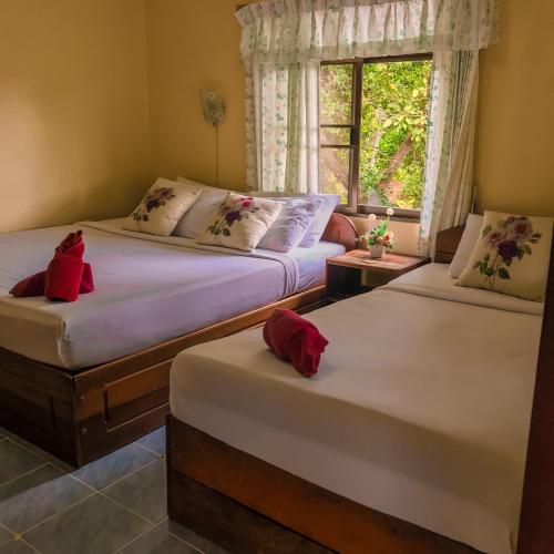 two twin beds in a room with a window at Tanouy Garden in Baan Khai