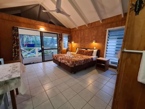 a bedroom with a bed and a large window at Sunny Beach Bungalows - Aitutaki in Amuri