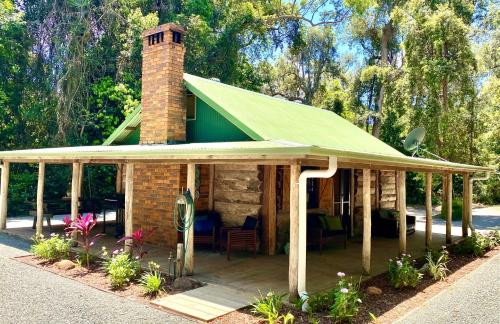 a house with a green roof and a brick chimney at Ferns Hideaway Resort in Byfield