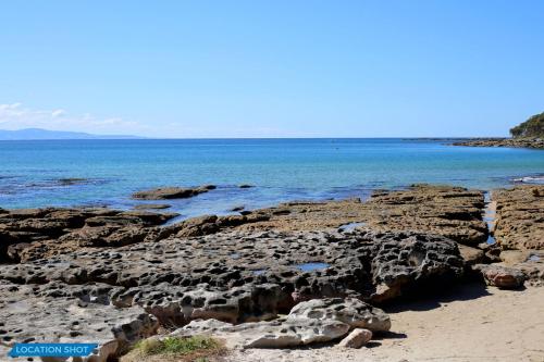 a beach with rocks and the ocean in the background at Sandy Feet Retreat I Pet Friendly I 1 Min Walk to Beach in Currarong