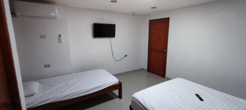 a bedroom with two beds and a tv on the wall at Posada Dakema in Cartagena de Indias