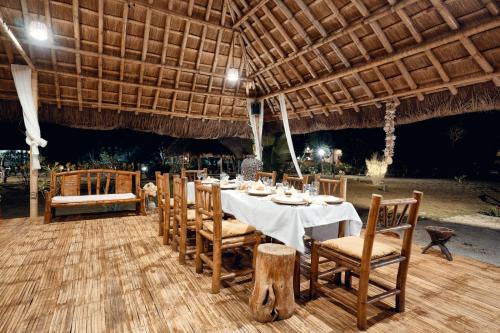 a dining table and chairs under a large umbrella at San Nicolas Private Beach in Busuanga