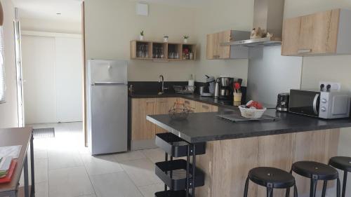 a kitchen with a counter with stools and a refrigerator at Gite des Cépages in Voiteur
