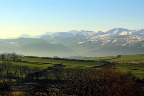 a green field with snow capped mountains in the background at The Eagles Bunkhouse in Betws-y-coed