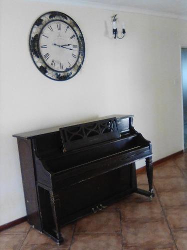a clock on the wall above a piano at Sugar Shack Backpackers Botswana in Gaborone