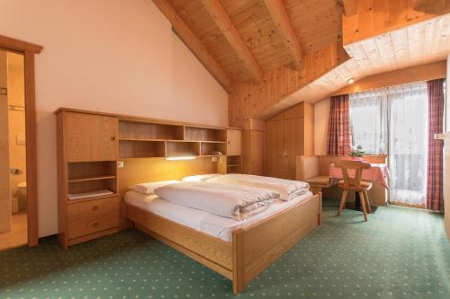 a bedroom with a large bed and a desk at B&B Apartments La Palsa in San Cassiano