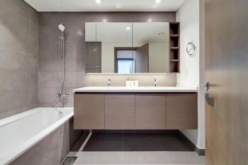 a bathroom with a tub and a sink and a mirror at Primestay - Creek Gate 2 in Dubai Creek Harbour in Dubai