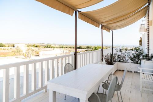 a white table on a balcony with a view of the ocean at MASSERIA SCALEDDA in Manduria