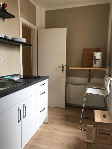a kitchen with white cabinets and a door and a stool at Ferienwohnung Eckloff in Lutherstadt Wittenberg