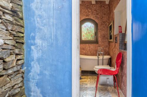 a bathroom with a red chair and a bath tub at Villa Sa Pintadera private pool in Stintino