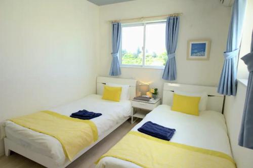 2 łóżka w sypialni z niebieskimi zasłonami i oknem w obiekcie Frennch House B022 w mieście Yaka