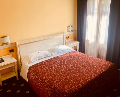 a bedroom with a bed with a red bedspread and a window at MOTEL Malpensa INN & Hotel-Airport in Tornavento