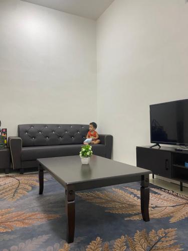 ein kleines Kind auf einer Couch im Wohnzimmer in der Unterkunft Cik Misi Homestay in Sik