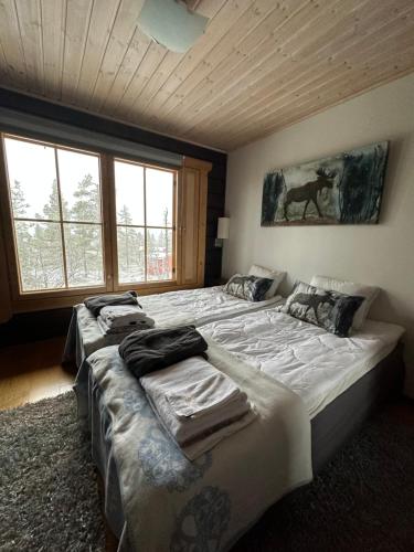 two beds in a room with two large windows at Villa Utsuntuisku in Levi