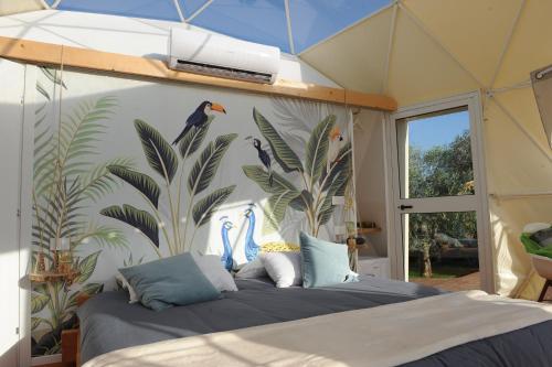 a bedroom with a bed with birds on the wall at Melograno Bubble Glamping in Vasanello