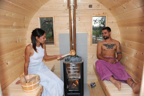 un uomo e una donna in una sauna con stufa a legna di Melograno Bubble Glamping a Vasanello