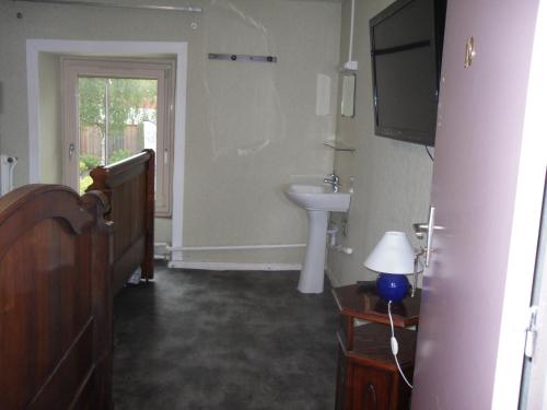 a bathroom with a sink and a toilet and a television at l'escale gourmande in Châlus