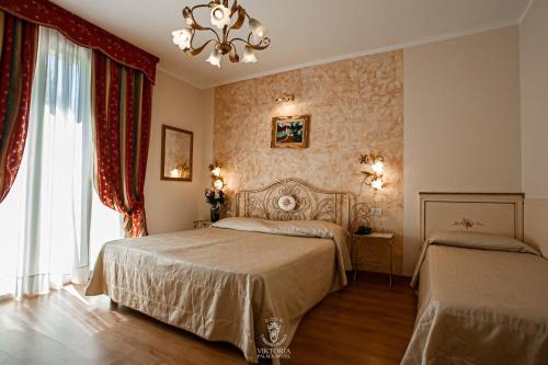 1 Schlafzimmer mit 2 Betten und einem Kronleuchter in der Unterkunft Viktoria Palace Hotel in Lido di Venezia