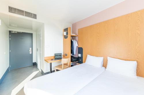 a hotel room with two beds and a desk and a door at B&B HOTEL Lieusaint Carré Sénart in Lieusaint