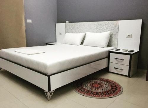 a bedroom with a large white bed with a rug at Kodra E Gjelber in Hundëkuq