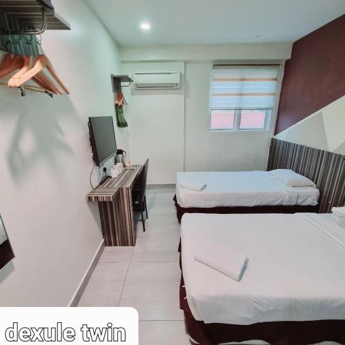 a hotel room with two beds and a television at Sunrise Golden Hotel in Kajang
