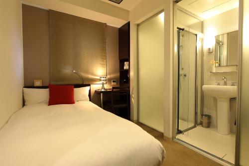 Hotel Massimo Mishima في ميشيما: غرفة نوم بسرير وحمام مع حوض