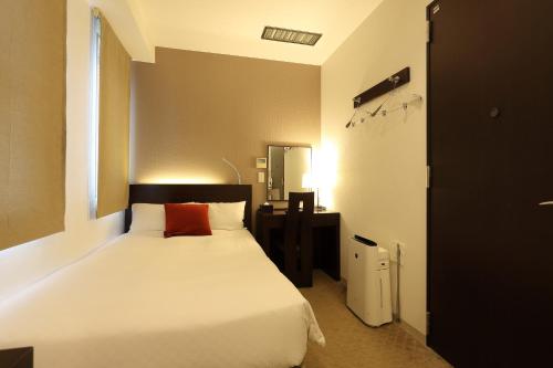 a bedroom with a white bed with a red pillow at Hotel Massimo Mishima in Mishima