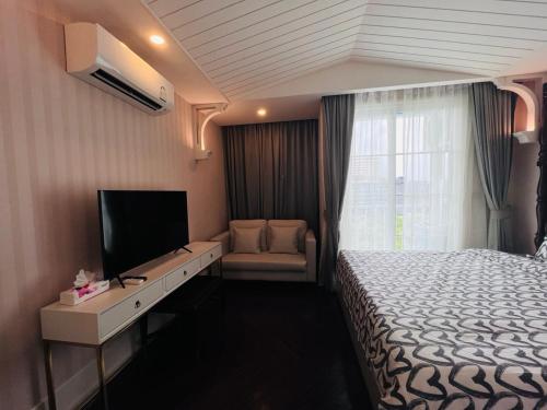 Habitación de hotel con cama y TV de pantalla plana. en FLORIDA GARDEN PATTAYA, en Na Jomtien