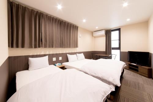 a hotel room with two beds and a tv at Le Studio 五条高倉 in Kyoto