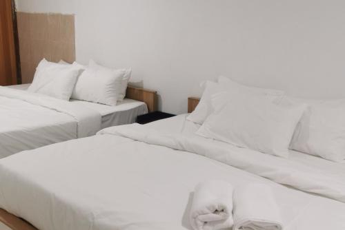 Duas camas num quarto com lençóis e almofadas brancos em Tang Hotel em Alor Setar