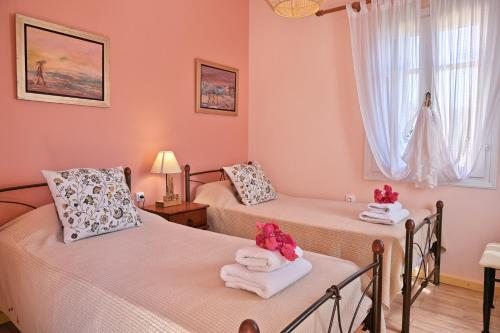 two beds in a room with pink walls at Villa Ireni Waterfont in Fiskardho