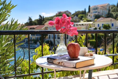 a table with an apple and books on a balcony at Villa Ireni Waterfont in Fiskardho