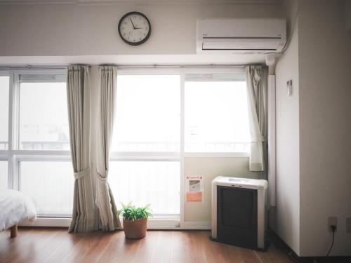 a bedroom with two large windows and a clock on the wall at SP HOTEL in Sapporo