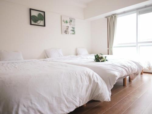 two beds in a bedroom with white sheets and a window at SP HOTEL in Sapporo