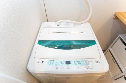 a washing machine in a corner of a room at Yokkaichi Motomachi Hotel in Yokkaichi