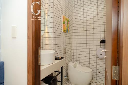 La salle de bains est pourvue de carrelage blanc, de toilettes et d'un lavabo. dans l'établissement Galaxy Hotel 3, à Hô-Chi-Minh-Ville