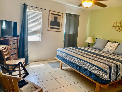 a bedroom with a bed and a tv and a chair at My Ohana - 30 days in Kailua-Kona