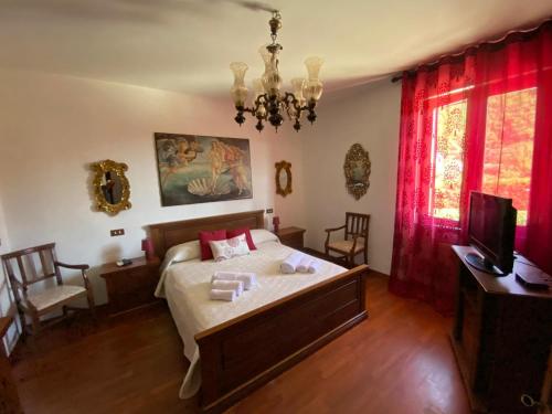 a bedroom with a bed with red curtains and a television at Villa con piscina tra Versilia e Cinque Terre in Luni