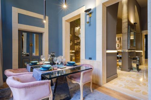 a dining room with a table and two pink chairs at Maison Boutique At Viviana in San Pietro in Lama