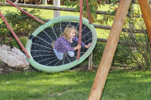 a little girl is sitting on a swing at Bio-Bauernhof Samerhof in Mariapfarr