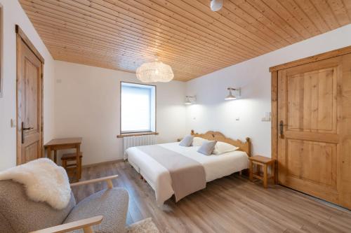 a bedroom with a white bed and a wooden ceiling at La Charbonnière, grand gîte haut-de-gamme avec jacuzzi et sauna in Gérardmer