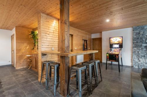 un bar con taburetes en una habitación con paredes de madera en La Charbonnière, grand gîte haut-de-gamme avec jacuzzi et sauna, en Gérardmer