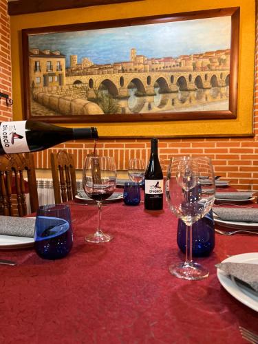 a bottle of wine sitting on a table with wine glasses at Hotel Puente de Piedra in Zamora